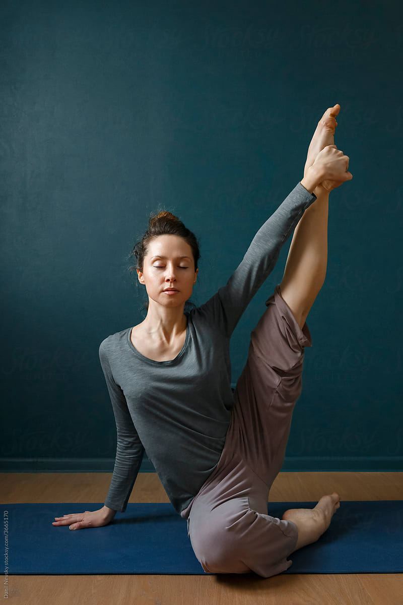 Slim woman sitting in yoga pose with leg raised