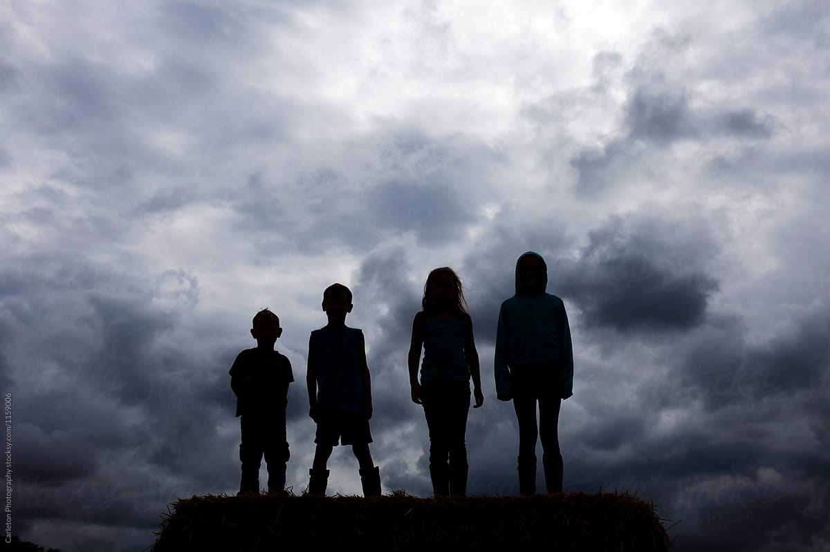 Four kids silhouetted against clouds