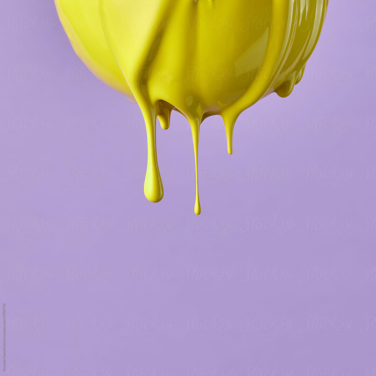 Yellow paint drips from a lemon on a purple background