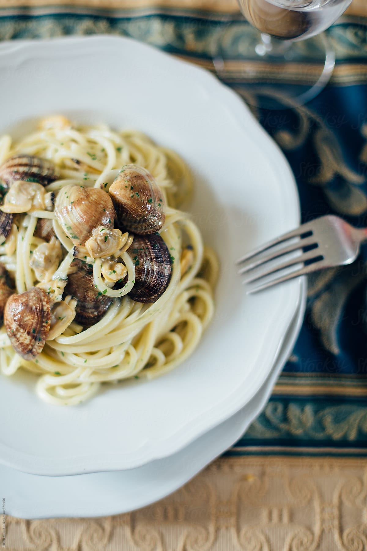 Overhead shot of spaghetti clams dish with fork on furnished table