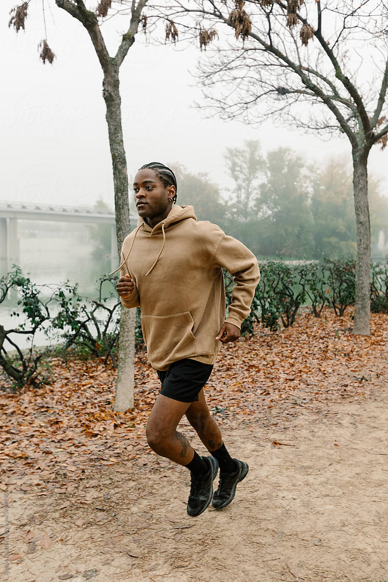 Black man runs along the trails of a public park on a foggy morning