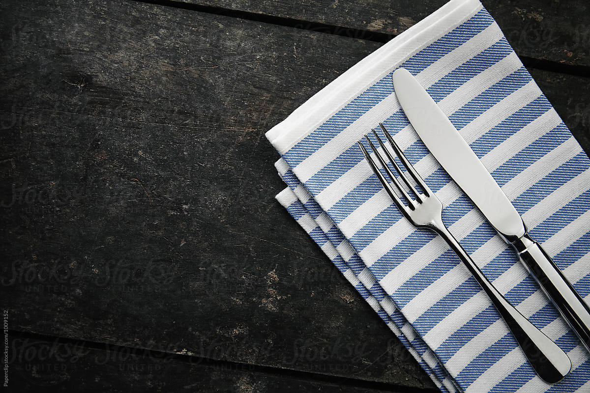 Silver cutlery and a napkin on dark wooden table