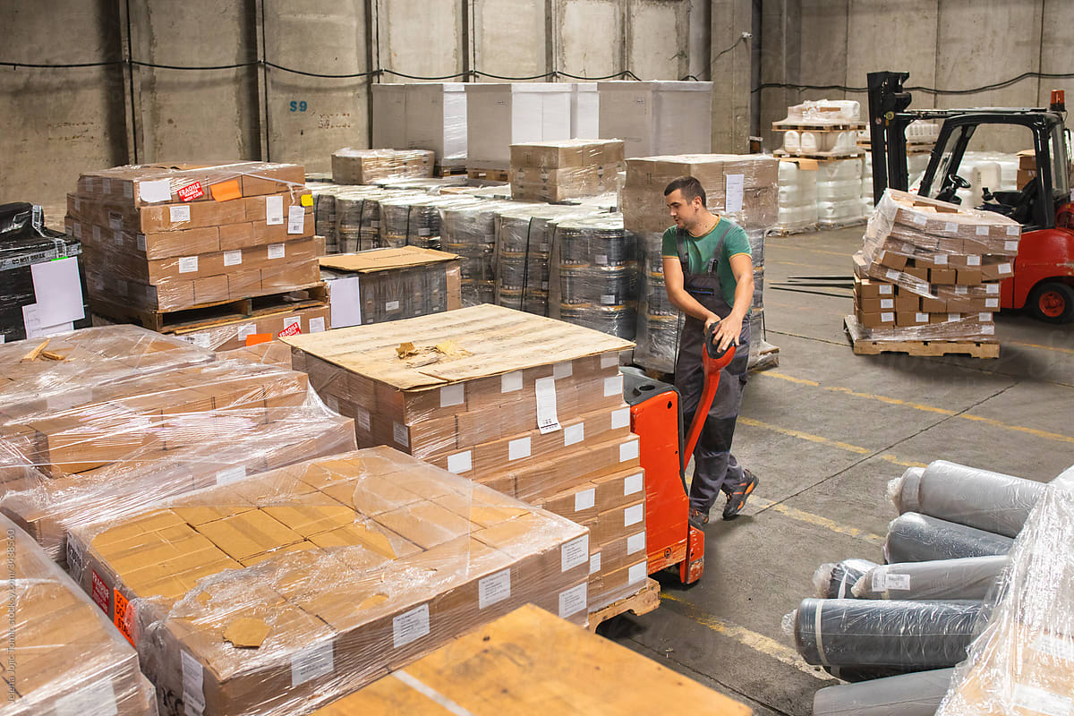 One man operates the pallet jack in a warehouse full of shipping goods