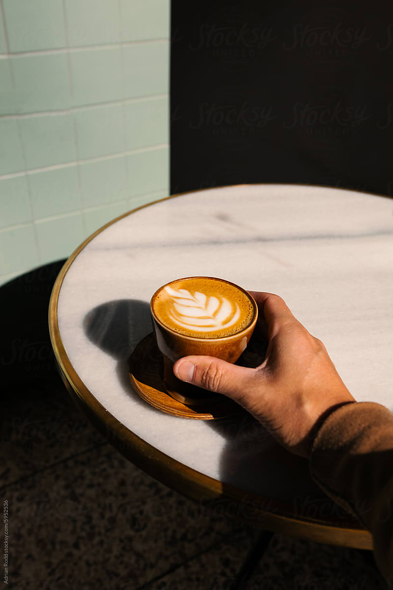 Hand holding a cup of specialty coffee decorated with latte art