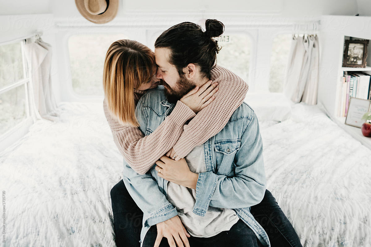 Cute hipster couple cuddling in converted school bus tiny home