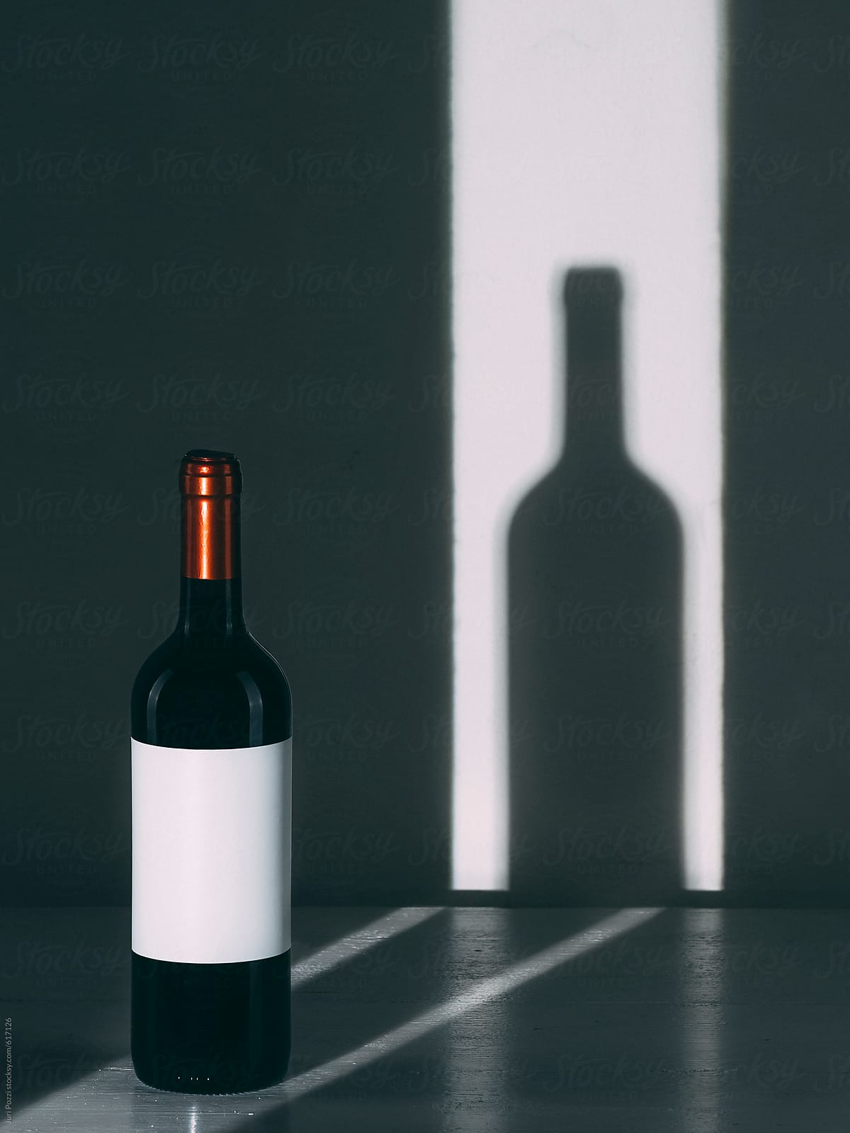 a wine bottle and its shadow on a wall