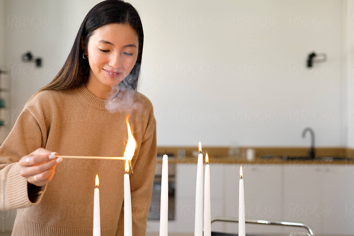 A young woman lights candles on the Christmas table