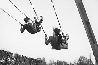 Girl Sitting On A Swing Flying High In The Blue Sky | Stocksy United