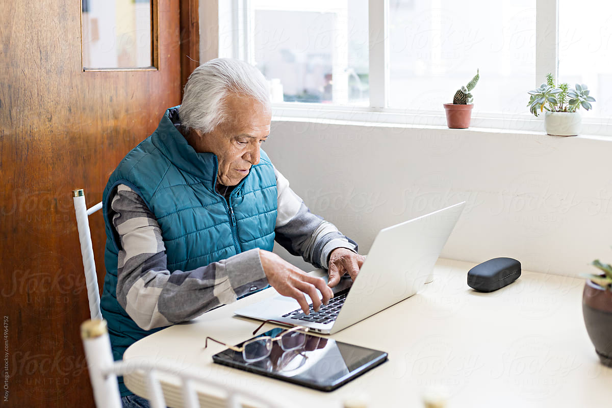 Old man working from home with laptop and tablet