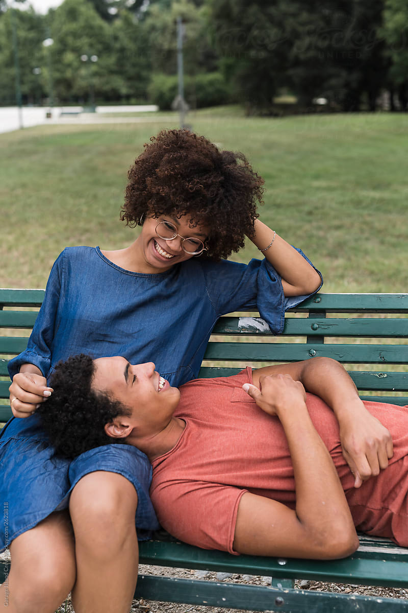 Happy young black couple sitting on the bench at the park