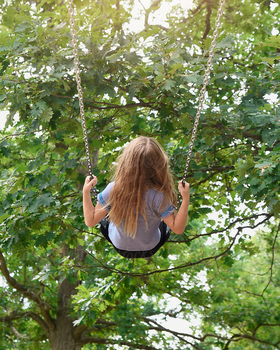 Girl Swinging High on Swing Outside with Summer Trees