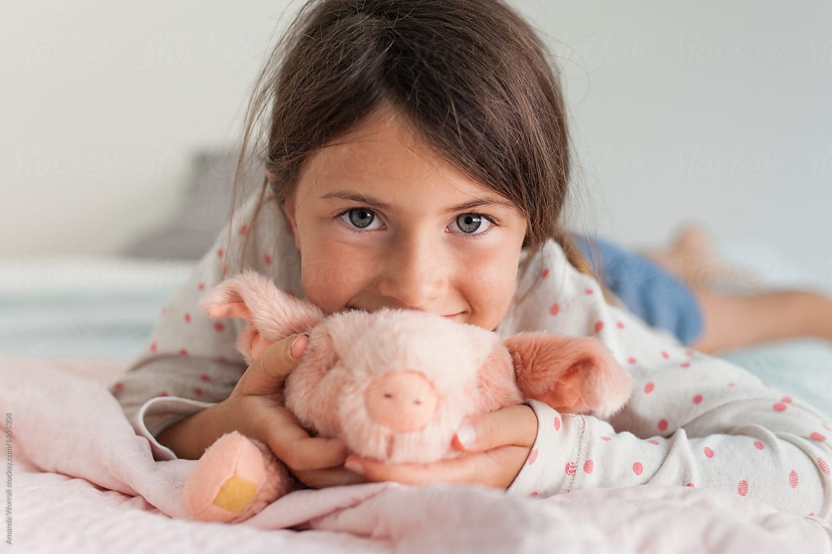 Happy girl hugging a stuffed pig in her room at home