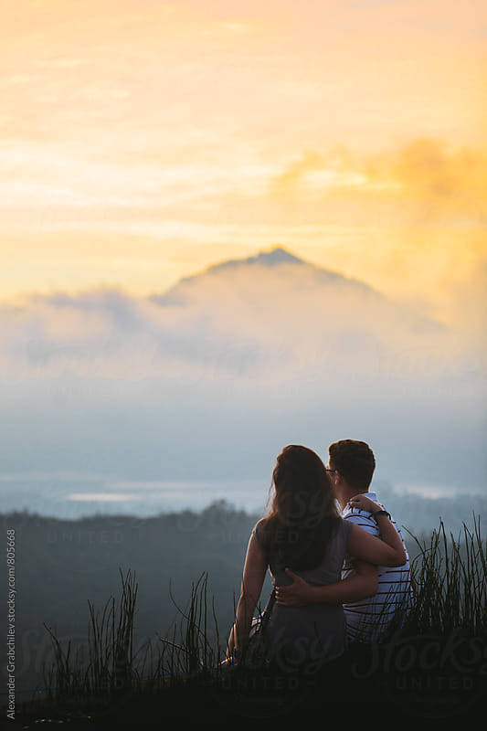 young couple watching sunrise in mountains