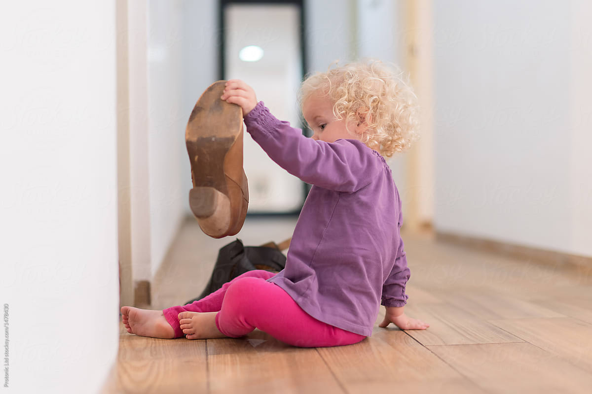 Toddler girl playing with her mom's shoe