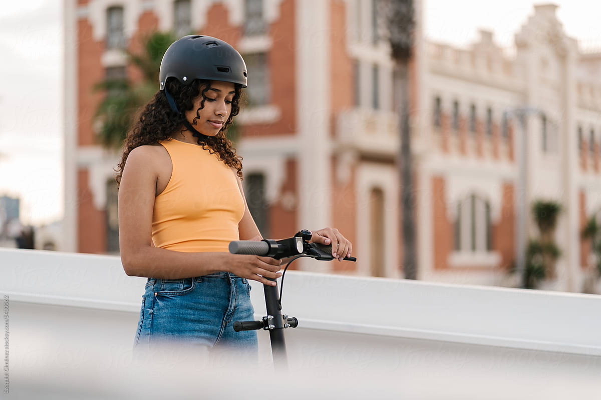 Black woman starting electric scooter in city
