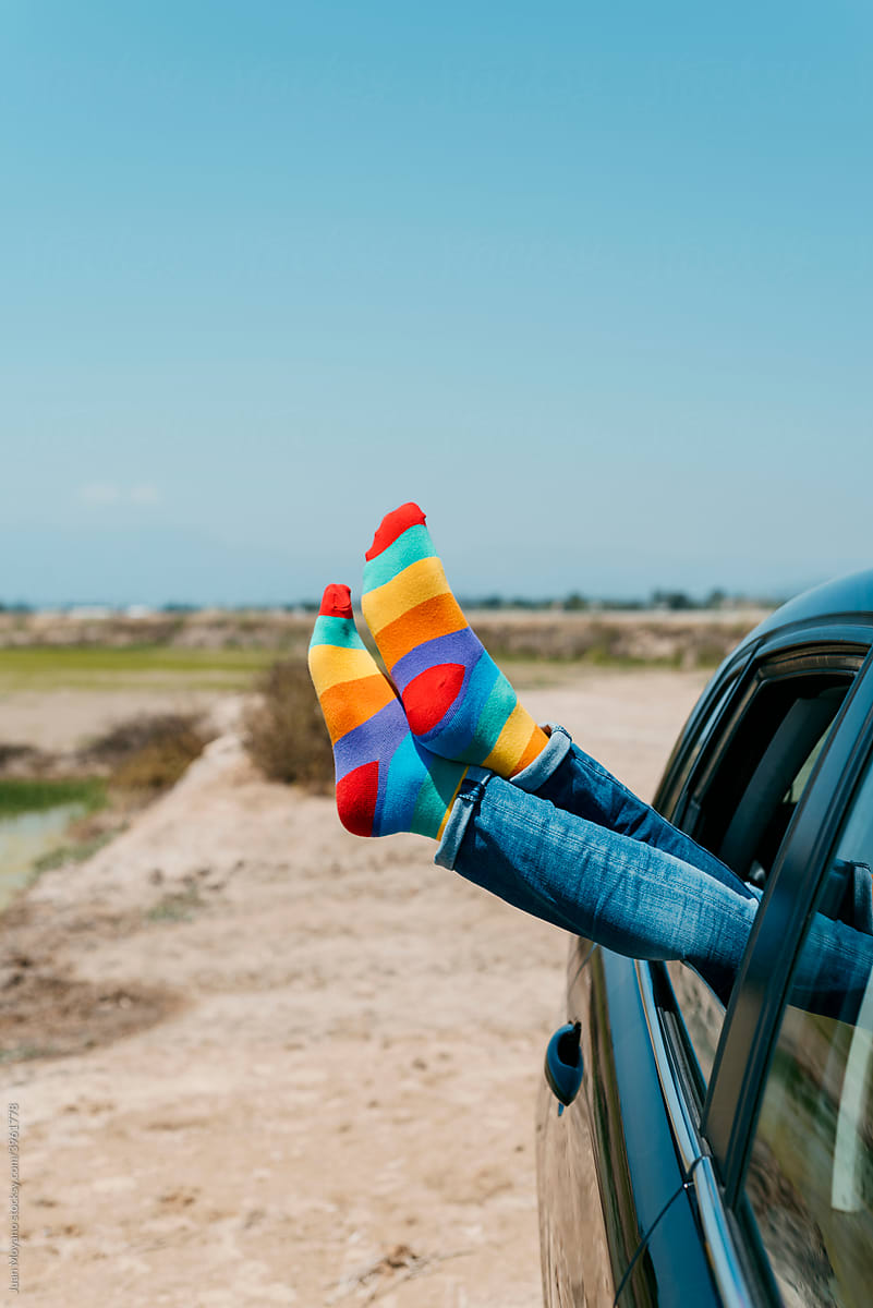 man wearing rainbow socks relaxing on the back seat of a car