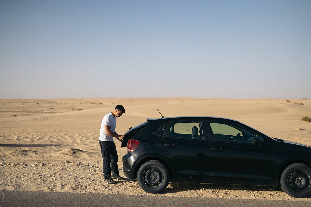 Man standing next to a car in the desert