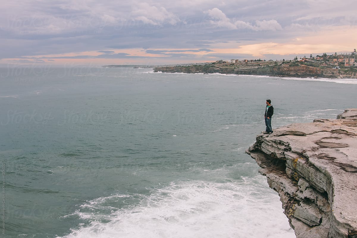 Young man on the edge of a cliff looking to the sea - Sydney, Australia