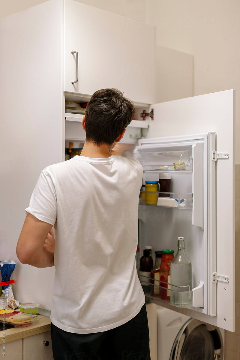 Man stands in front of an open fridge.