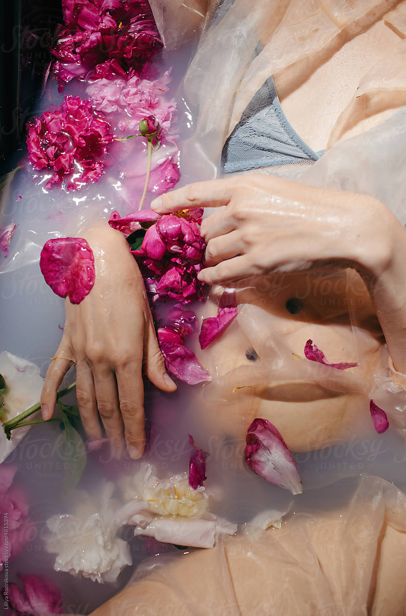 faceless sensual woman in milky bath with pink peony flowers