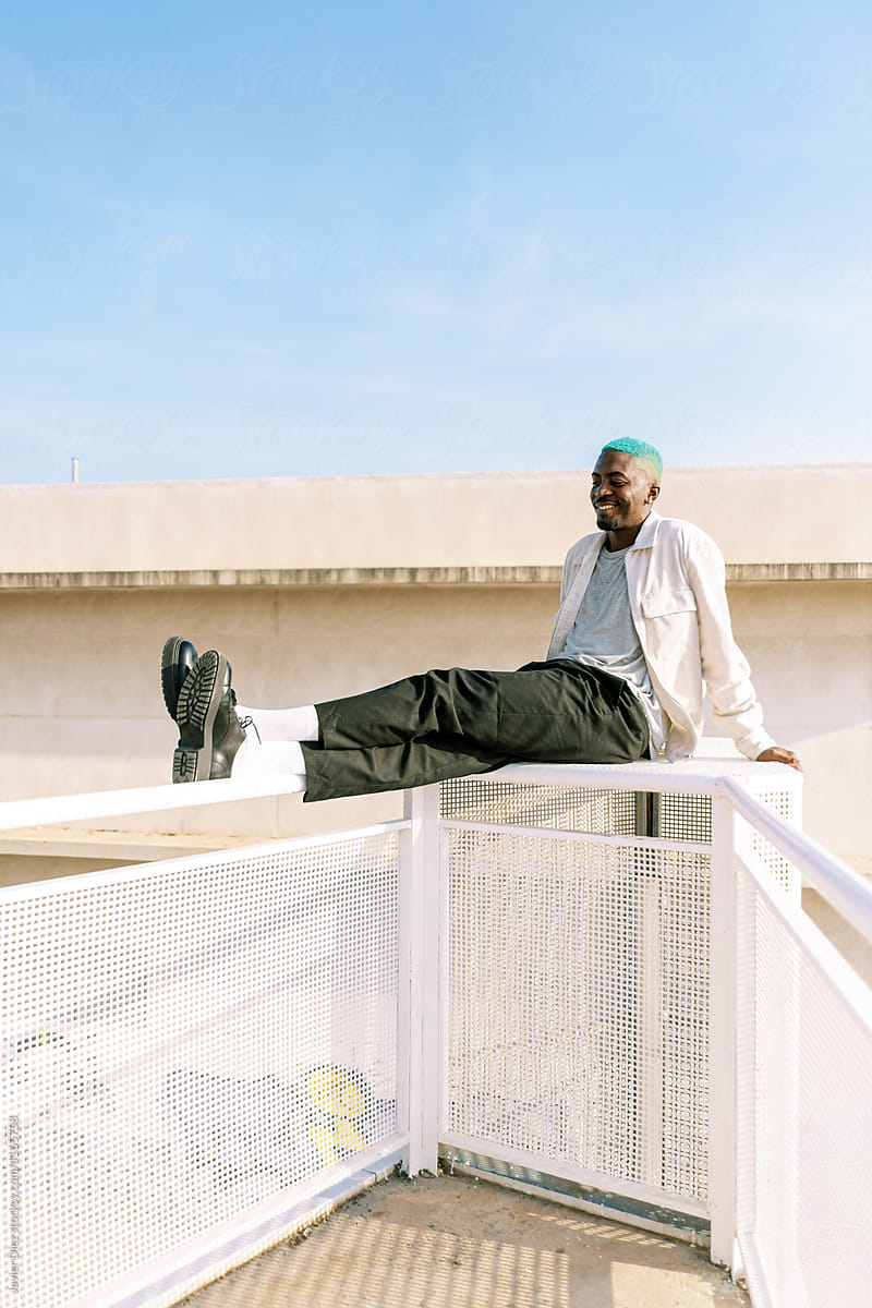 Trendy black man sitting on metal fence