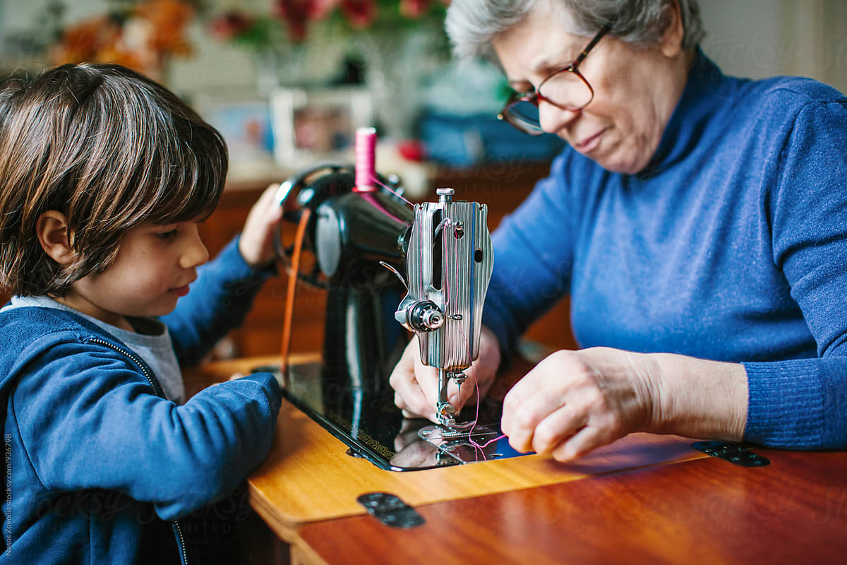 Grandson watching his grandmother working on a sewing machine