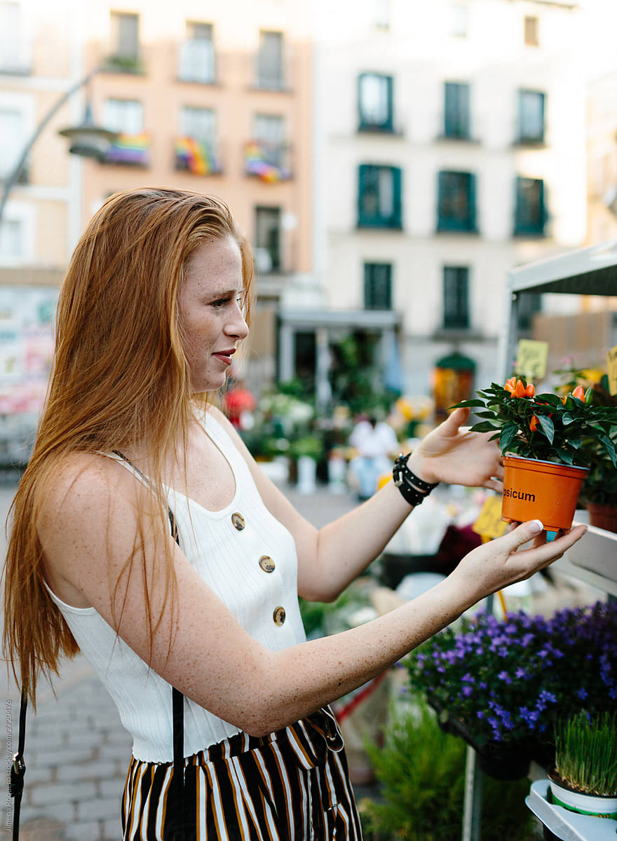 Woman choosing a plant to buy in a city street flower stall.