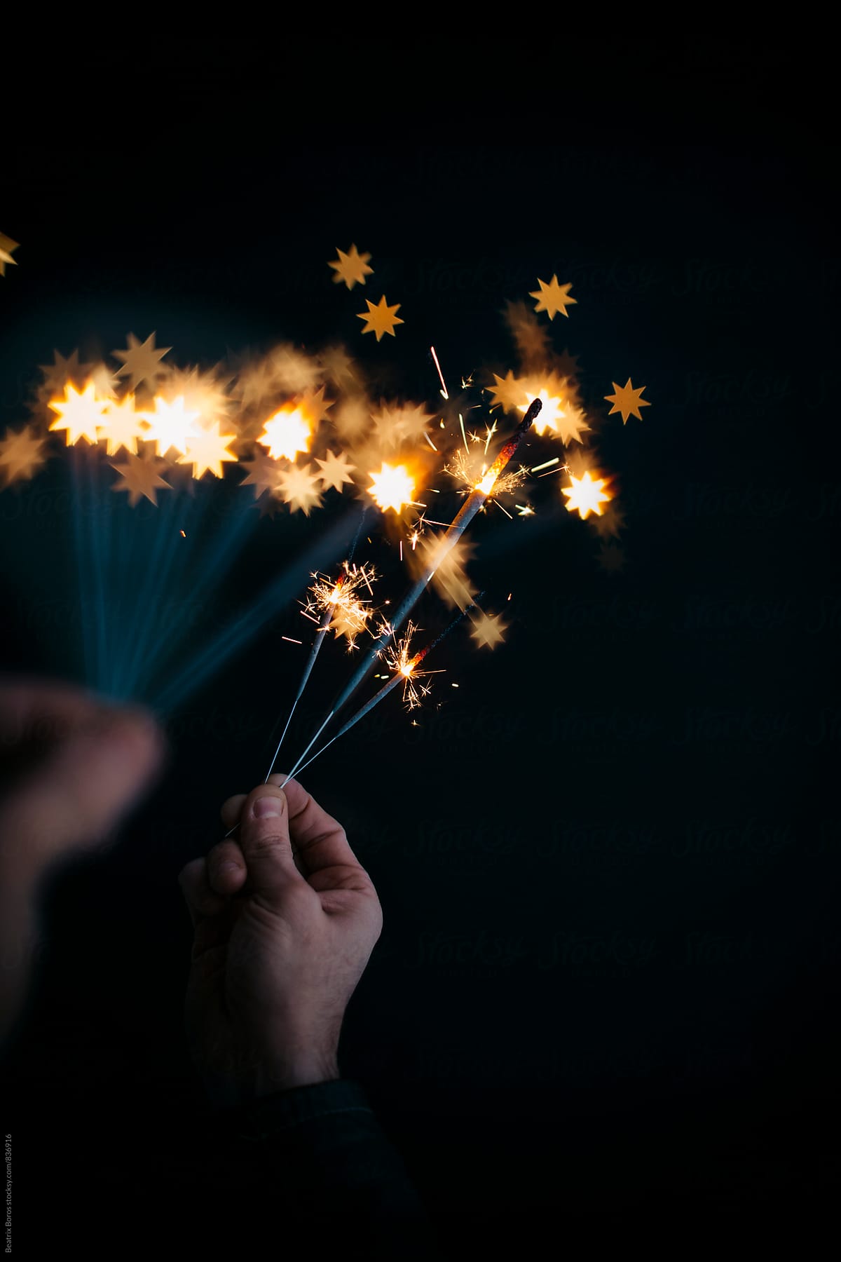 Man\'s both hands with sparklers, the further ones creating heart shaped bokeh