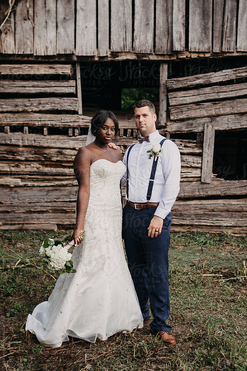 Wedding Couple Posed in front of Rustic Structure