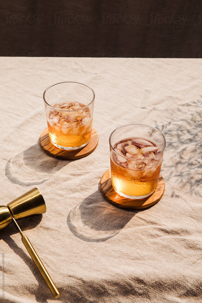 Two iced whiskey glasses near golden double jigger