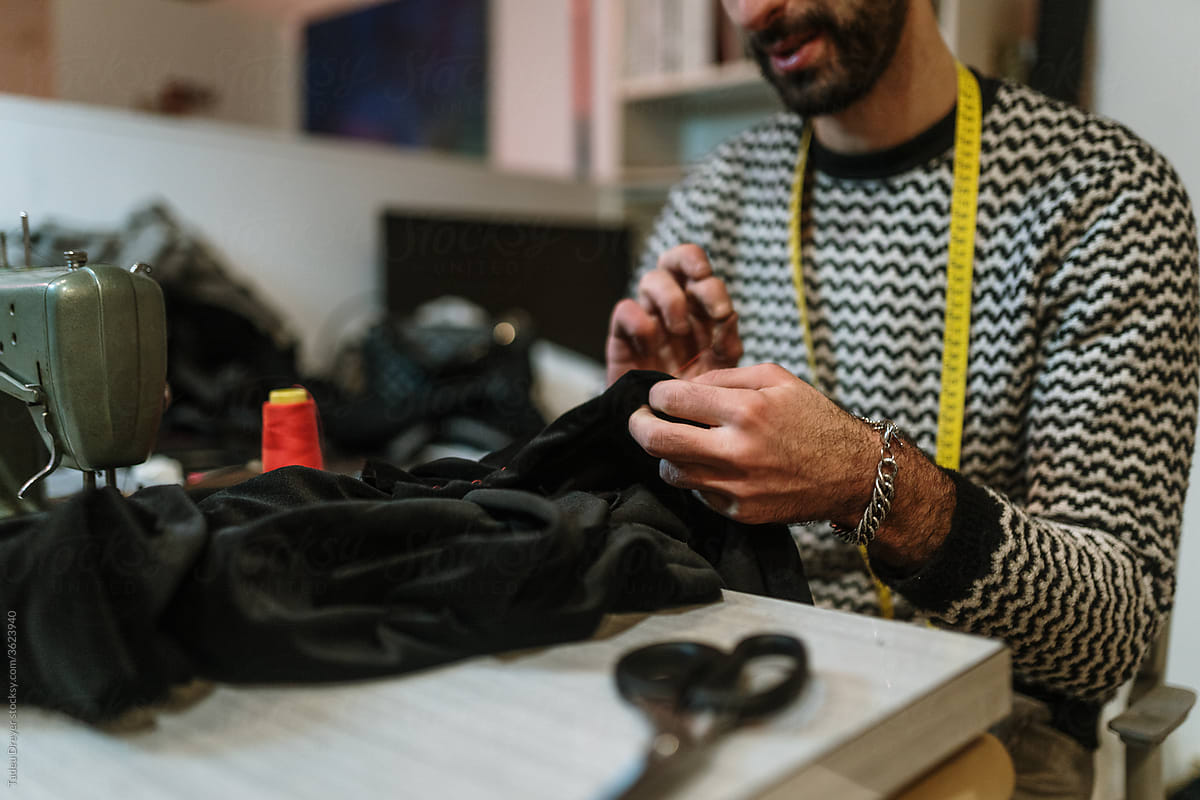 Faceless man stitching a clothing
