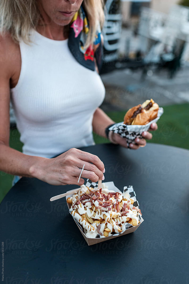 Customer eating smash burger and french fries in a food truck
