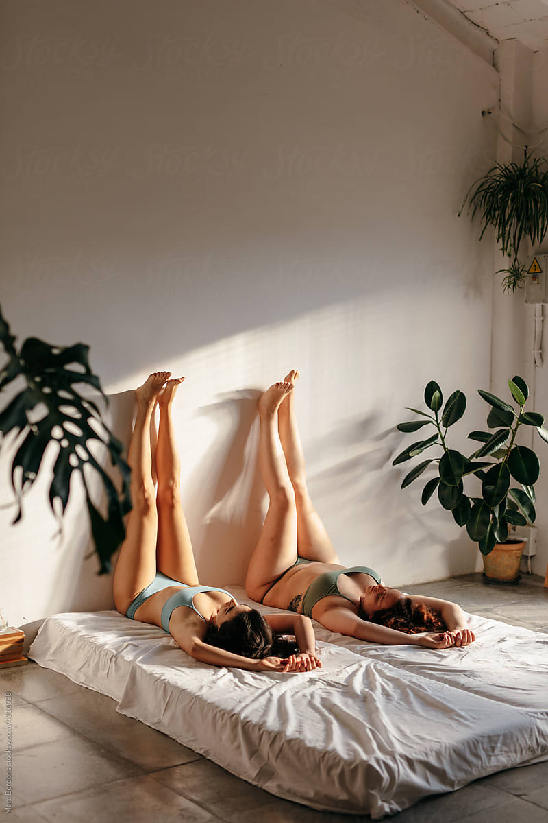 Two girls lying on the bed with their legs up