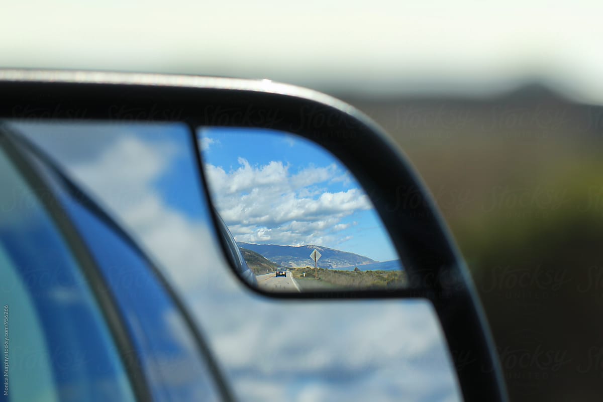 Road, sky and clouds in rear view mirror