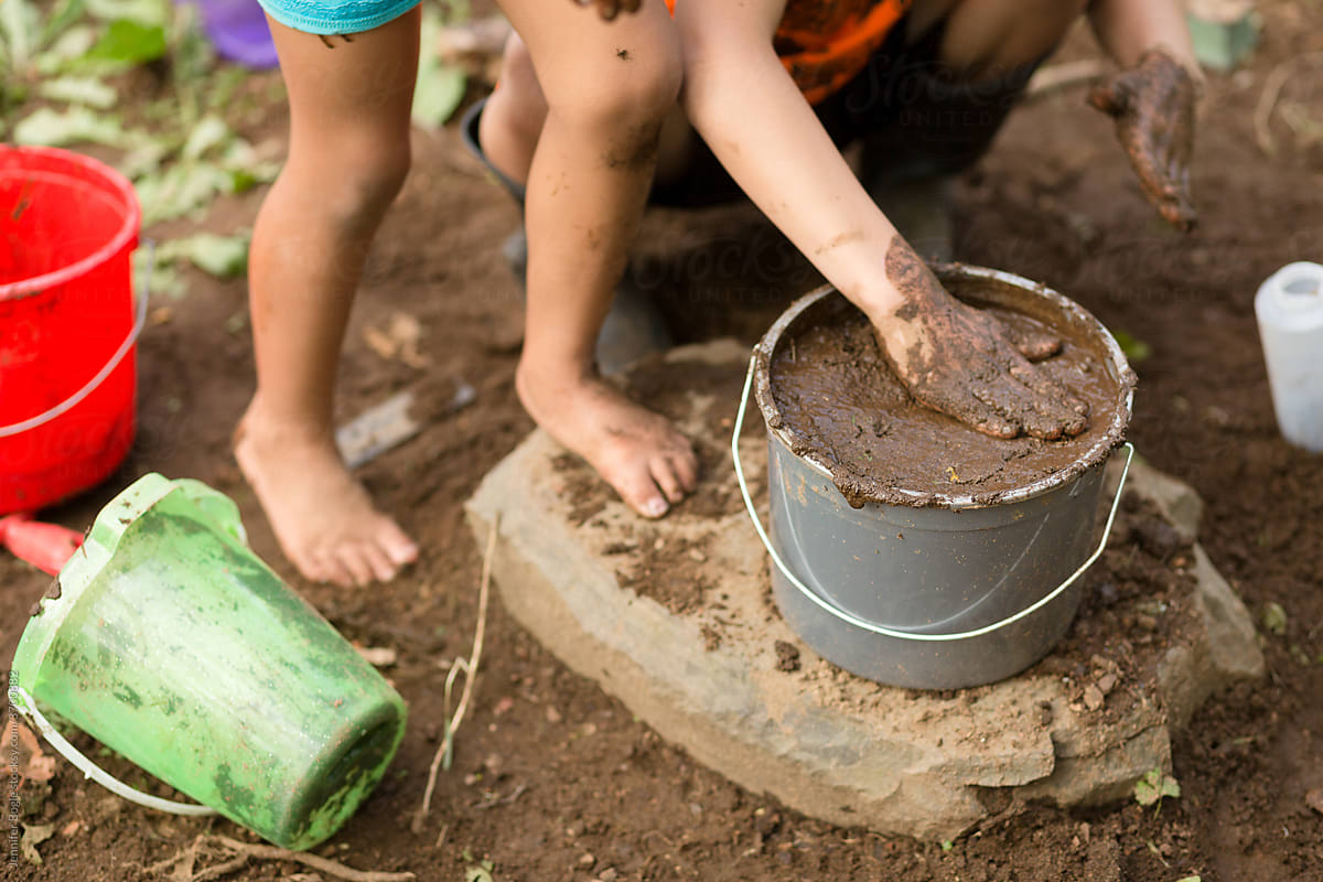 Children play with bucket of mud