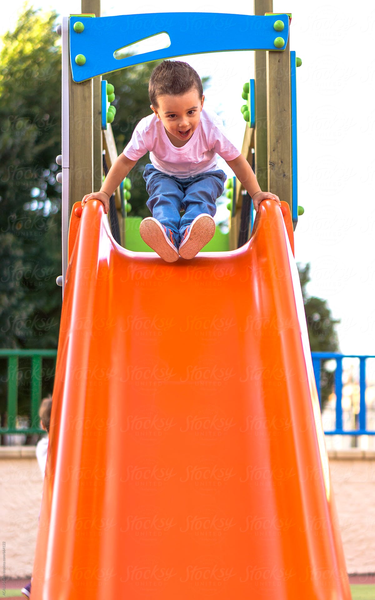 Child Sliding Down A Slide In A Playground by Stocksy Contributor ACALU  Studio - Stocksy