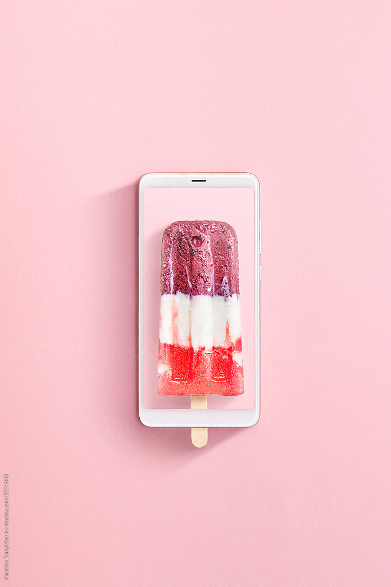Colorful berries milk ice-cream with a modern smartphone on a light pink background. Flat lay.