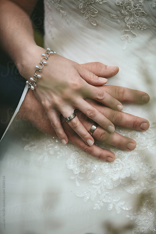 detail of a bride is stroking her grooms hand with wedding rings