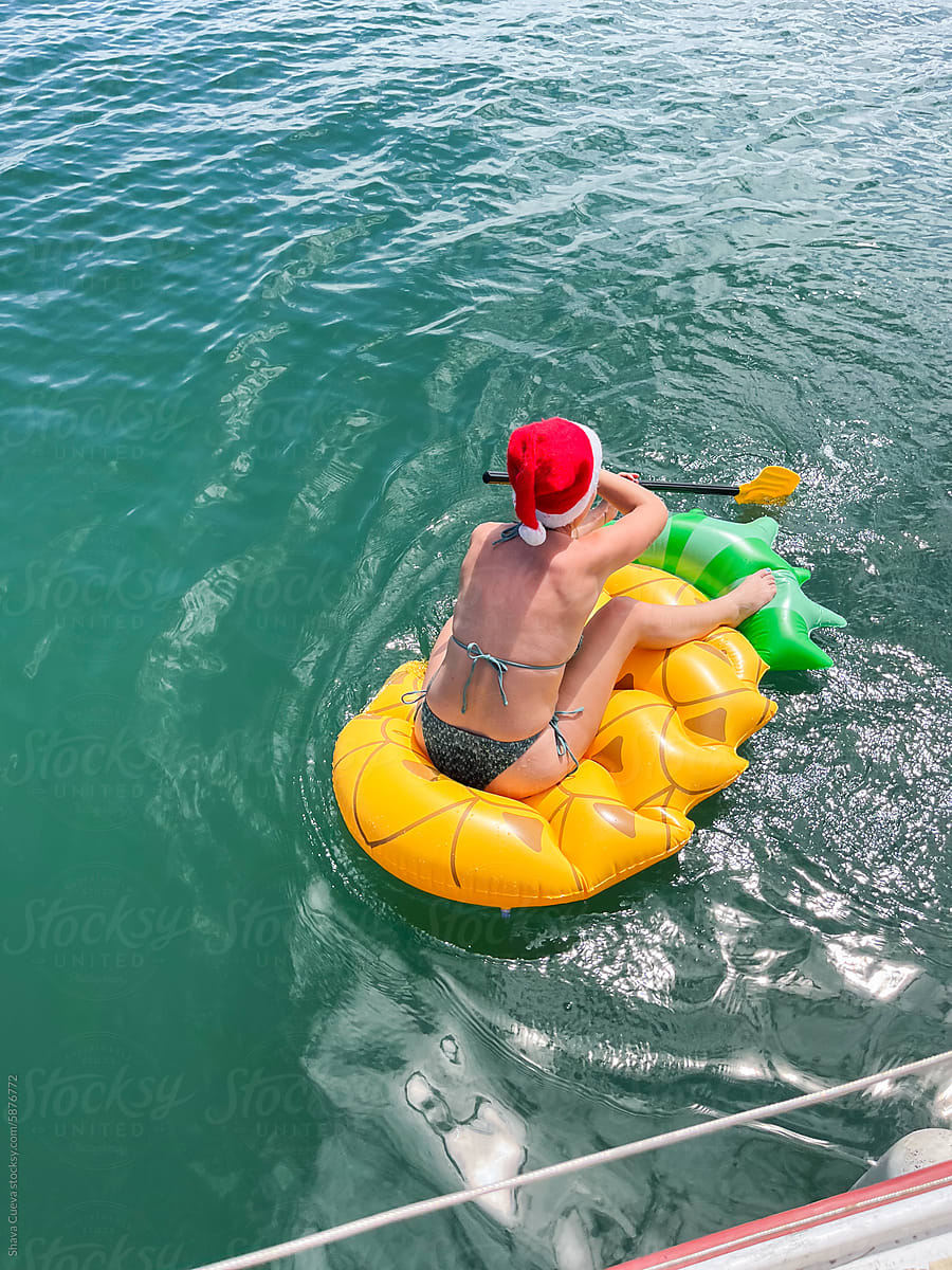 A woman with a Christmas beanie playing on an inflatable fruit