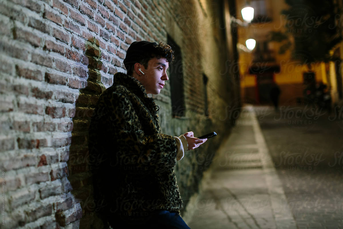 Young person at night  listening to music in the street