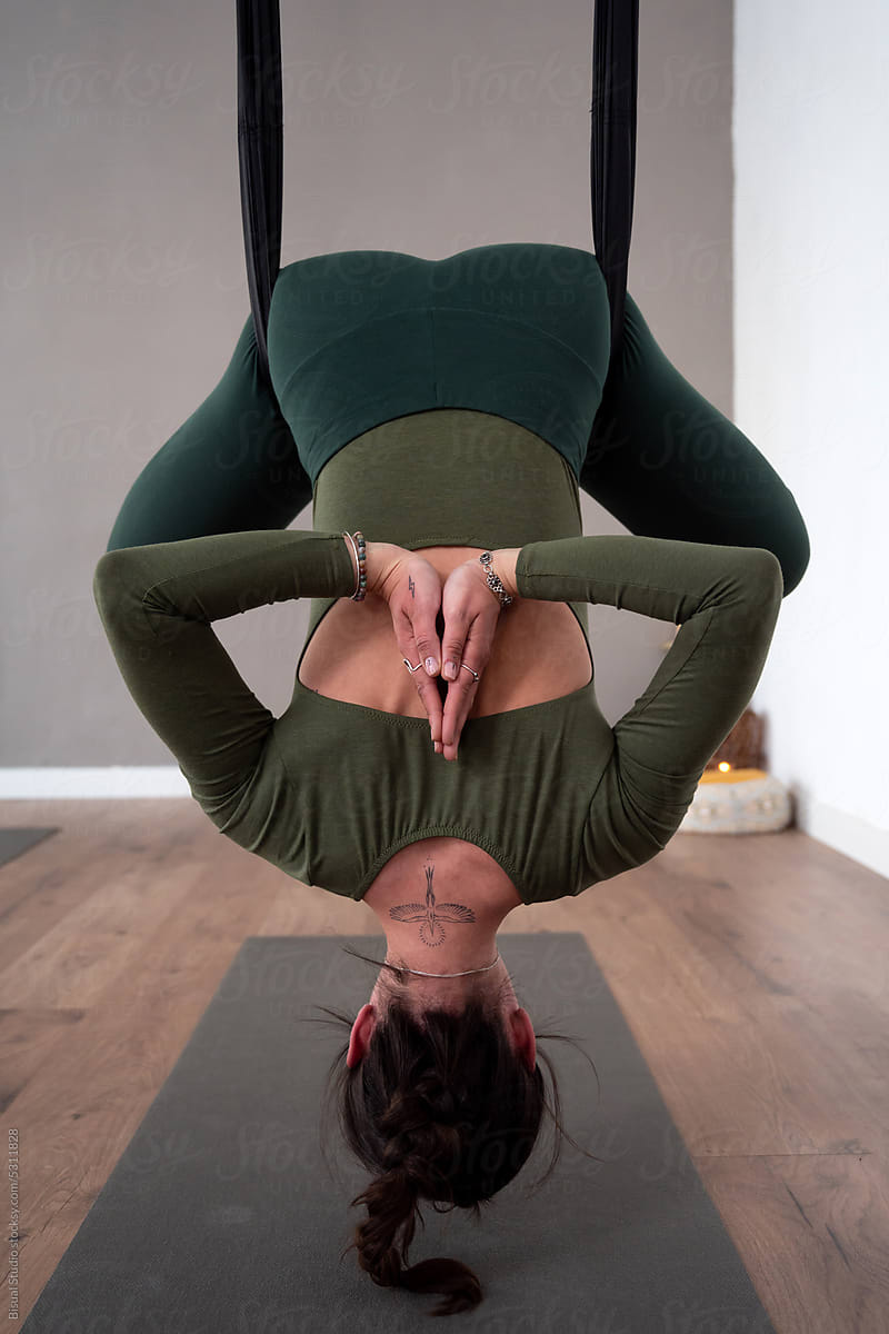 Woman practicing aerial yoga in lotus pose