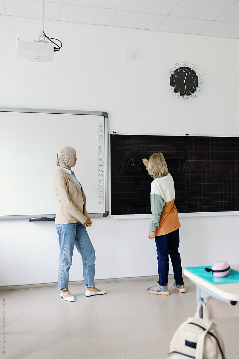 Multicultural teacher pupil junior school blackboard task