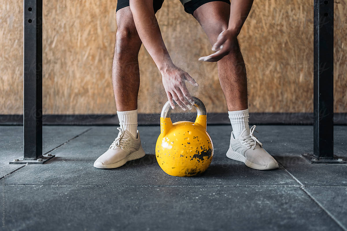 Crop male athlete lifting kettlebell