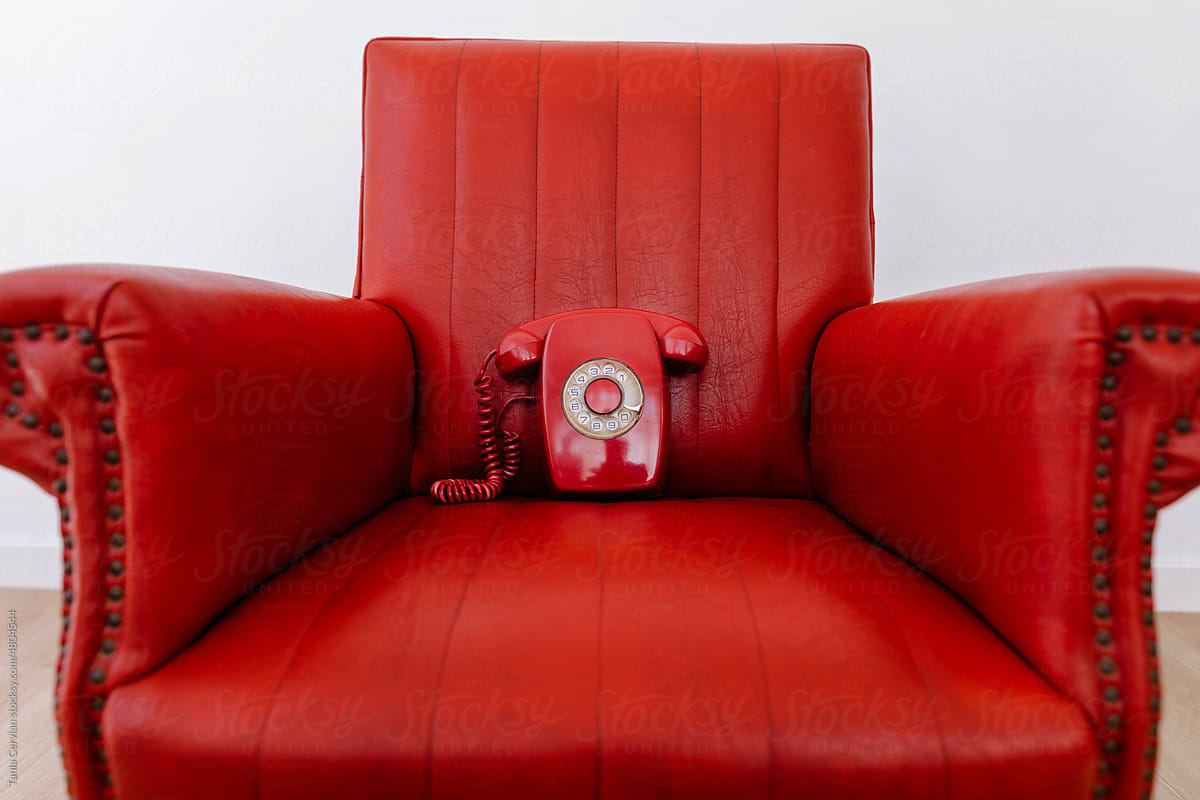 Red vintage armchair with old phone on top