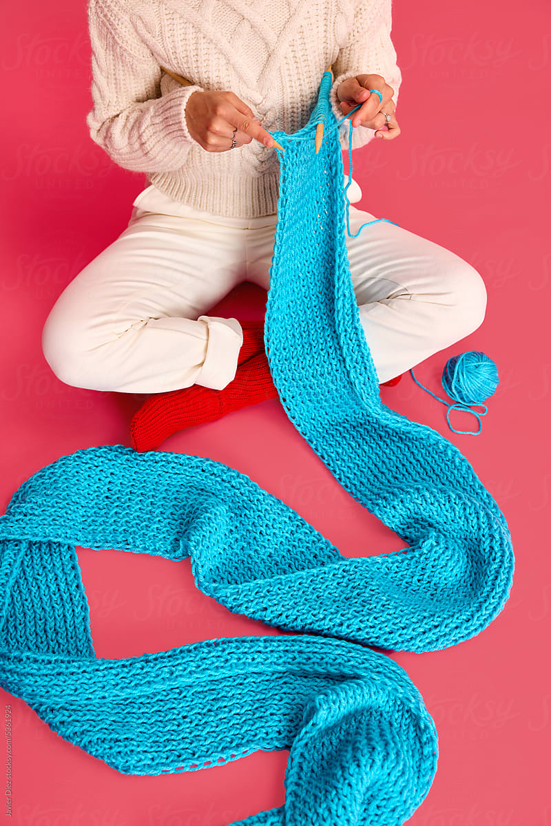 Lady knitting scarf sitting on floor in studio