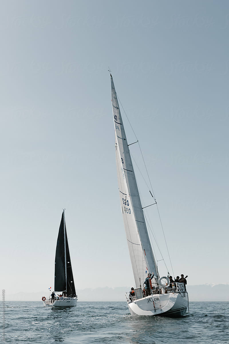 two sailboats with black and white sails out on the ocean in yacht race