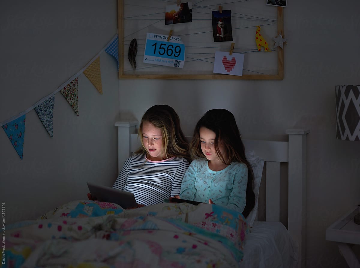 Kids faces lit up by device screens at night time