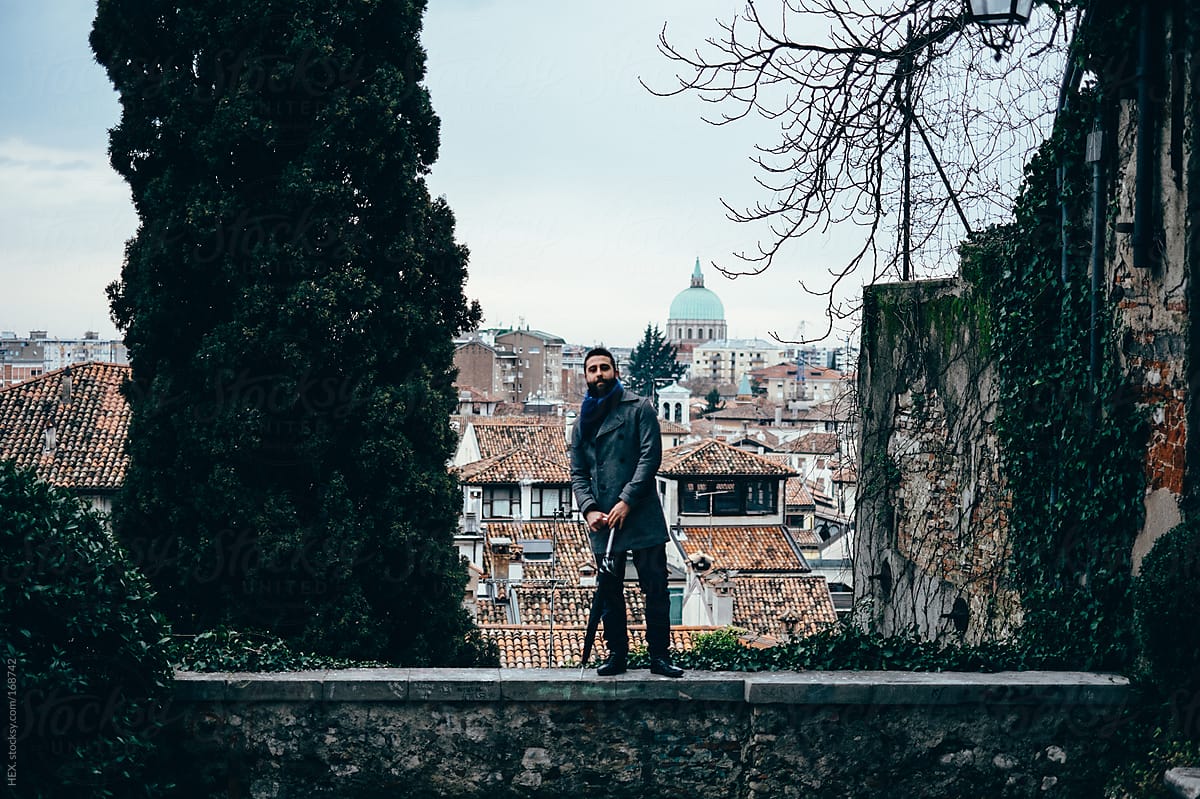 Handsome Man Standing On a Wall In Front Of an Italian City
