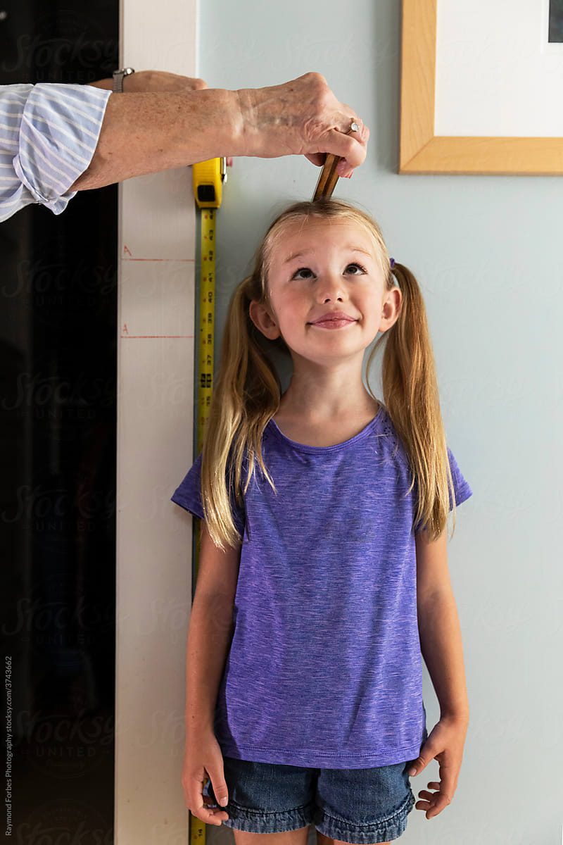 Young Girl Measuring her height with tape measure