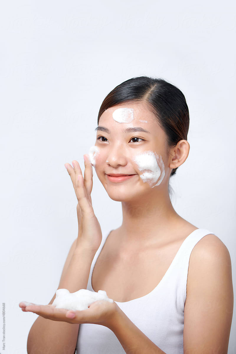 Waist up portrait of young pretty woman applying foaming cleanser